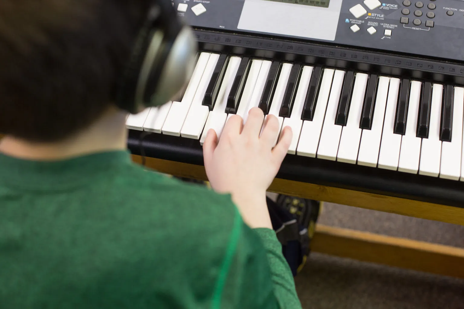 Young child learning piano at keyboard